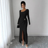Woman in black long-sleeve ribbed maxi dress with side slit and belted waist, fitted style
