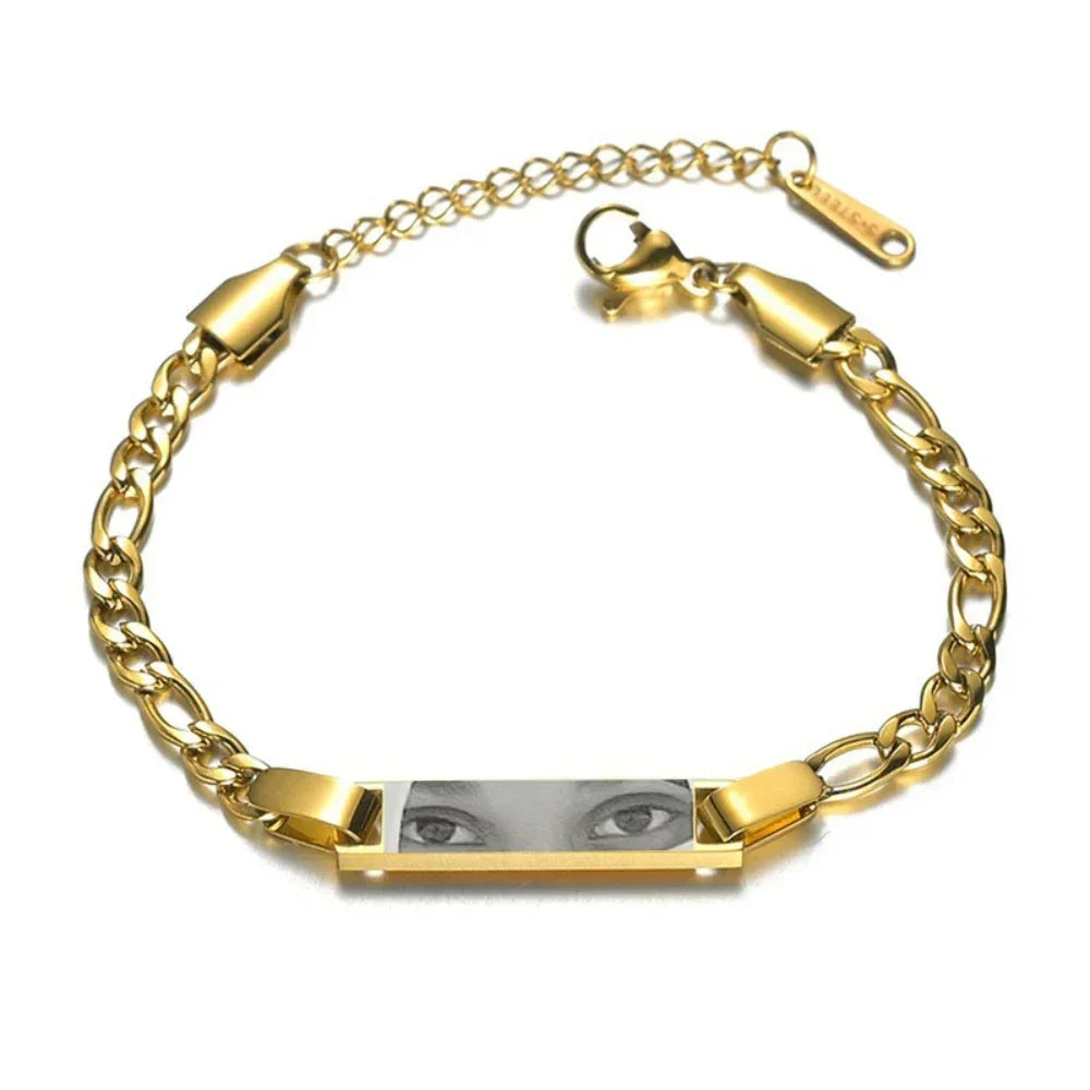 Gold chain bracelet with engraved plate featuring black and white eye illustration, adjustable fit