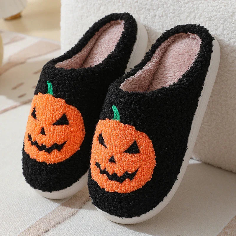 Cozy black fleece slippers with orange pumpkin face design and plush interior, slip-on style
