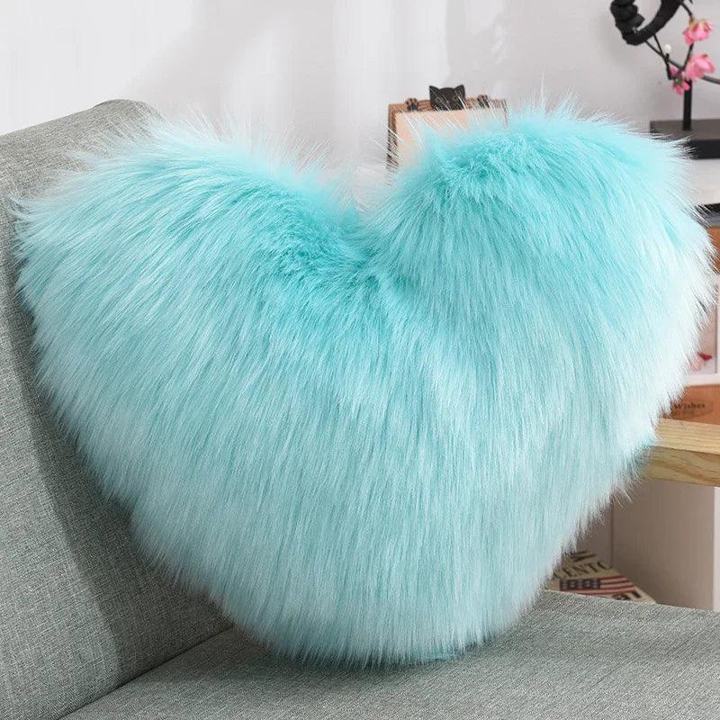 Fluffy aqua blue heart-shaped faux fur pillow on a modern gray sofa