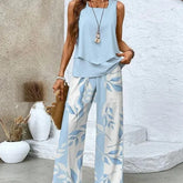Woman wearing a light blue sleeveless top with flowy, wide-leg white and blue leaf print pants
