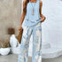 Woman wearing a light blue sleeveless top with flowy, wide-leg white and blue leaf print pants