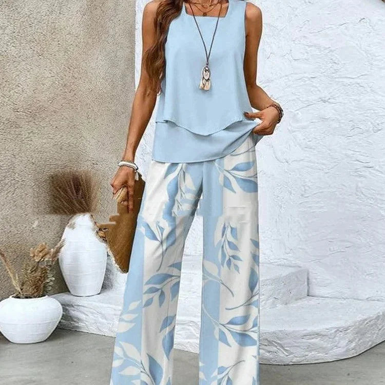 Woman wearing a light blue sleeveless top with flowy, wide-leg white and blue leaf print pants