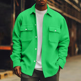 Man wearing a bright green oversized button-up shirt with front pockets, layered over a white t-shirt, styled in a casual streetwear fit.