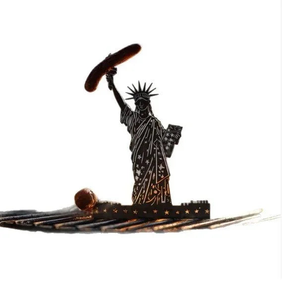 Metallic silhouette of Statue of Liberty holding a sausage, grill accessory on white background