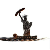 Metallic silhouette of Statue of Liberty holding a sausage, grill accessory on white background