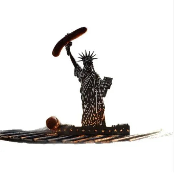 Metallic silhouette of Statue of Liberty holding a sausage, grill accessory on white background