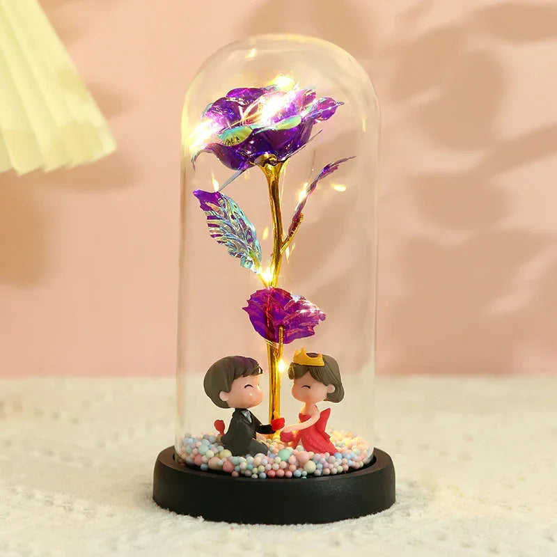 Encased purple and gold artificial rose with miniature figurines in a glass dome display
