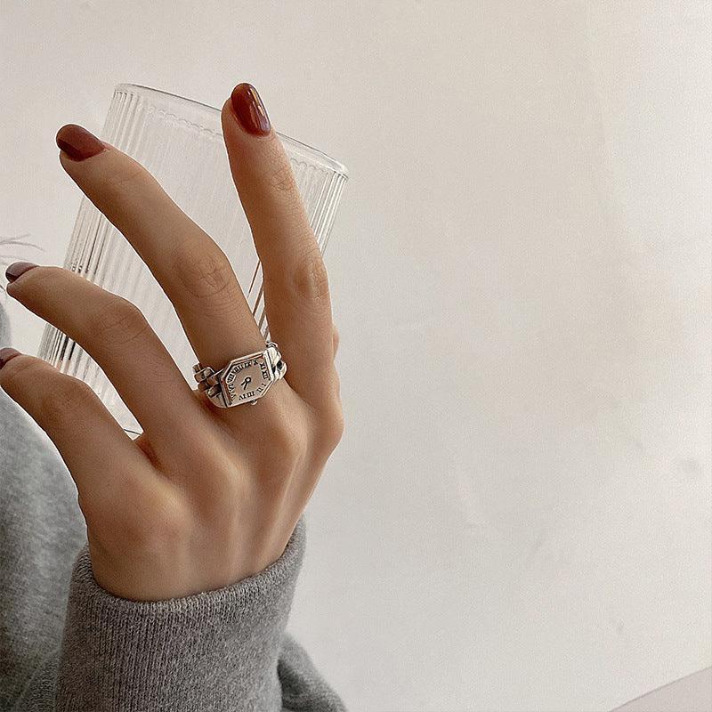 Silver geometric statement ring on hand, gray knit sleeve, minimalist streetwear style