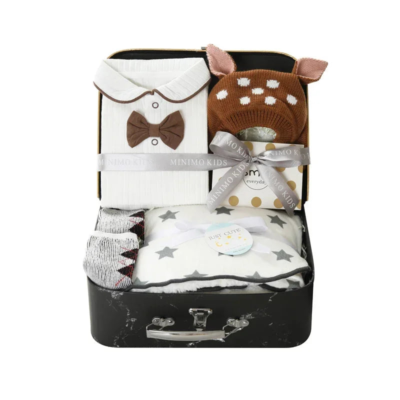 Baby gift set with white collared onesie, brown knit deer hat, socks, and star-patterned blanket in suitcase