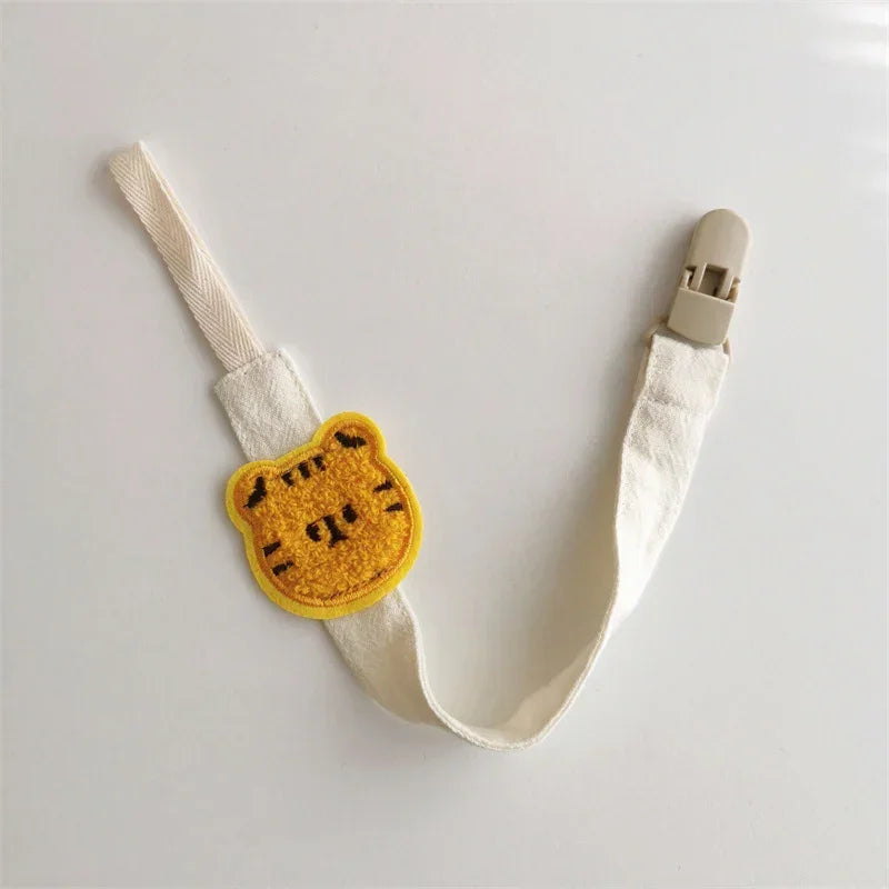 Cute yellow bear face patch on cream fabric strap with beige plastic clip, soft material