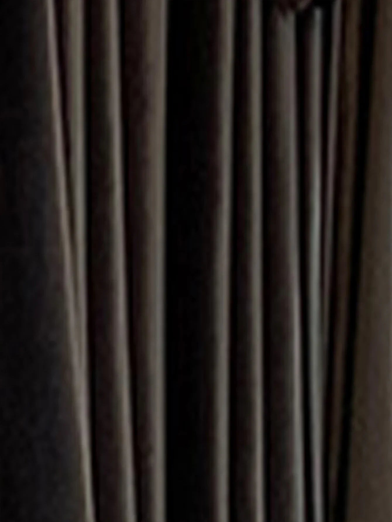 Close-up of black pleated fabric, smooth texture, modern streetwear clothing material