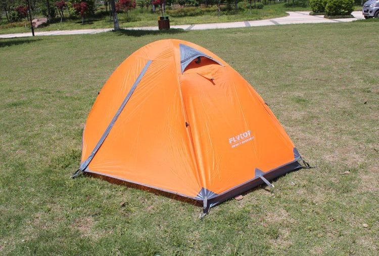 Orange dome tent with grey accents on grassy field, waterproof polyester material, outdoor camping shelter