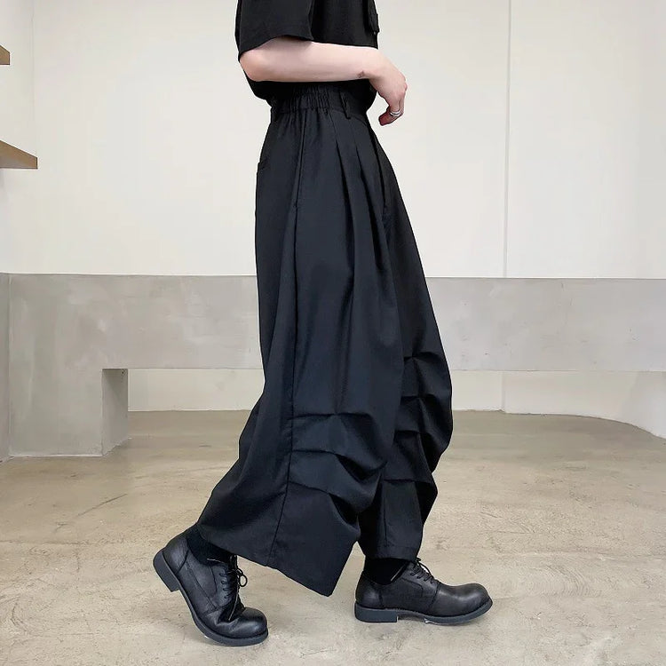Wide-leg black streetwear pants with pleated details, relaxed fit, and elastic waist