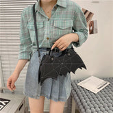 Woman in green plaid shirt and denim skirt with black bat-shaped shoulder bag
