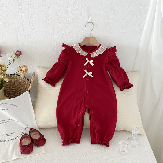 Red long-sleeve baby romper with ruffles, white collar, bow accents, and matching shoes
