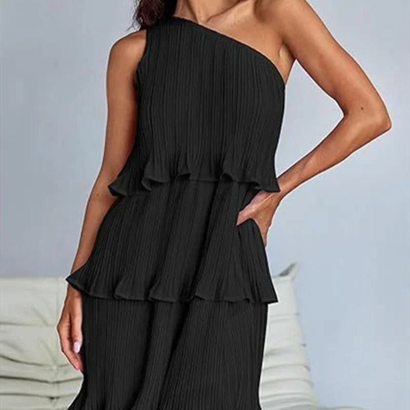 Woman wearing black one-shoulder pleated dress with tiered ruffles and relaxed fit