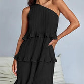 Woman wearing black one-shoulder pleated dress with tiered ruffles and relaxed fit