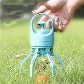 Hand holding a light blue plastic claw grabber tool with handle in grassy outdoor setting