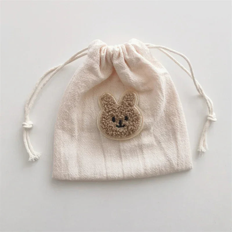 Beige cotton drawstring pouch with textured bunny face patch and soft fabric finish