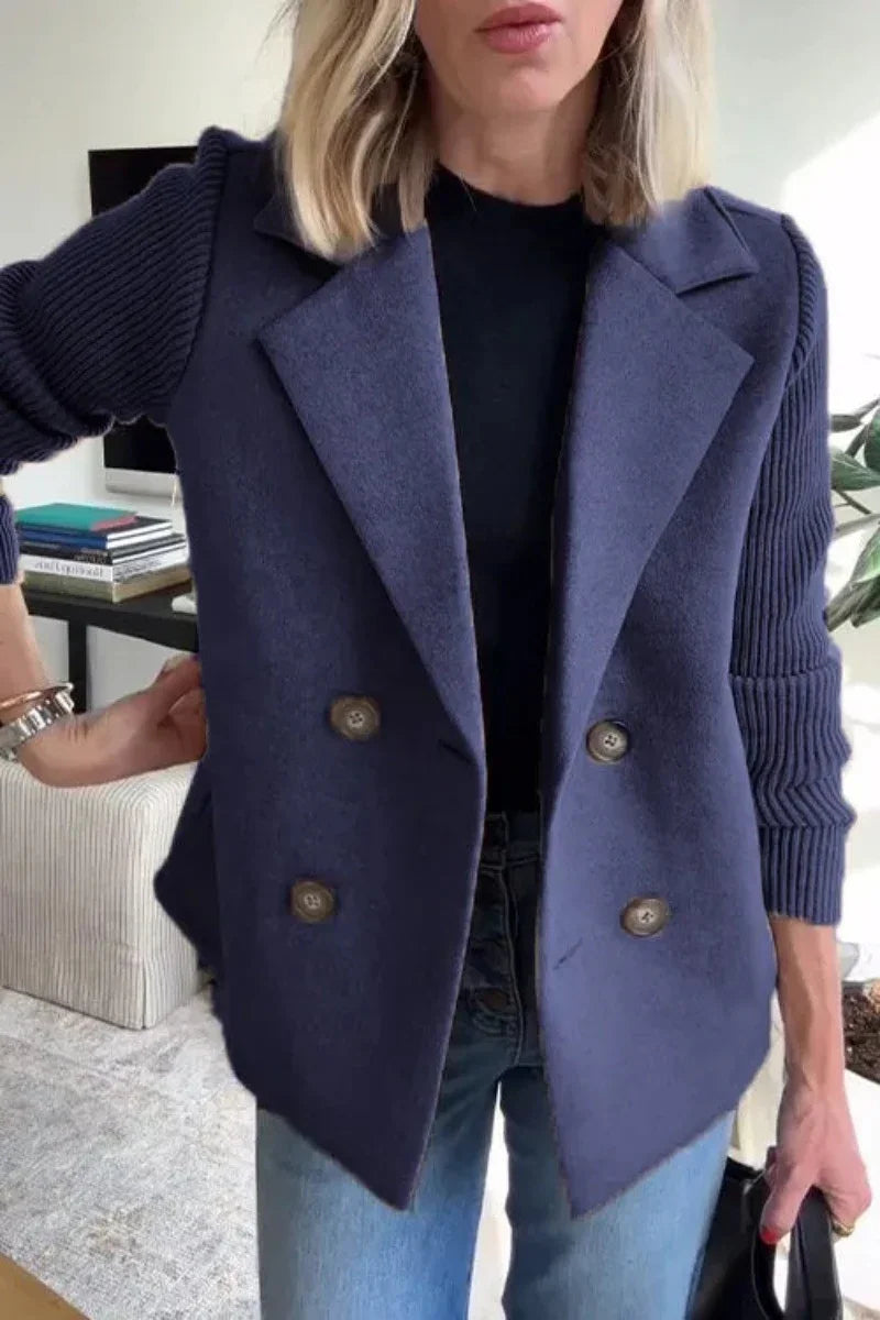 Woman wearing navy blue double-breasted wool blazer with ribbed knit sleeves, relaxed fit.