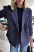 Woman wearing navy blue double-breasted wool blazer with ribbed knit sleeves, relaxed fit.