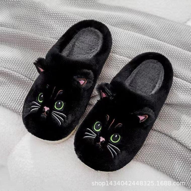Black plush slippers with cute cat face design, green eyes, cozy indoor fit.
