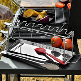 Stainless steel grilling rack with tray, tongs, and silicone brush on outdoor barbecue.