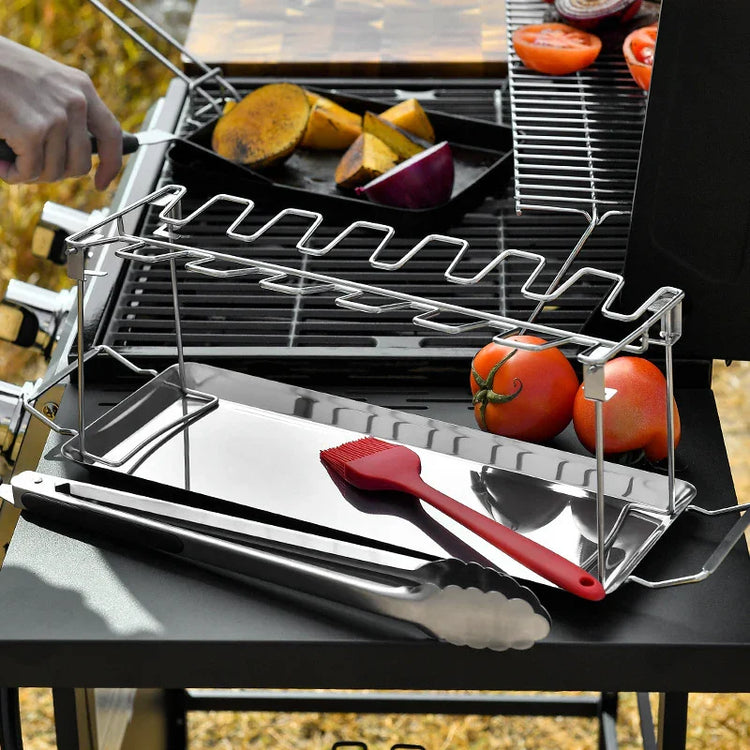 Stainless steel grilling rack with tray, tongs, and silicone brush on outdoor barbecue.