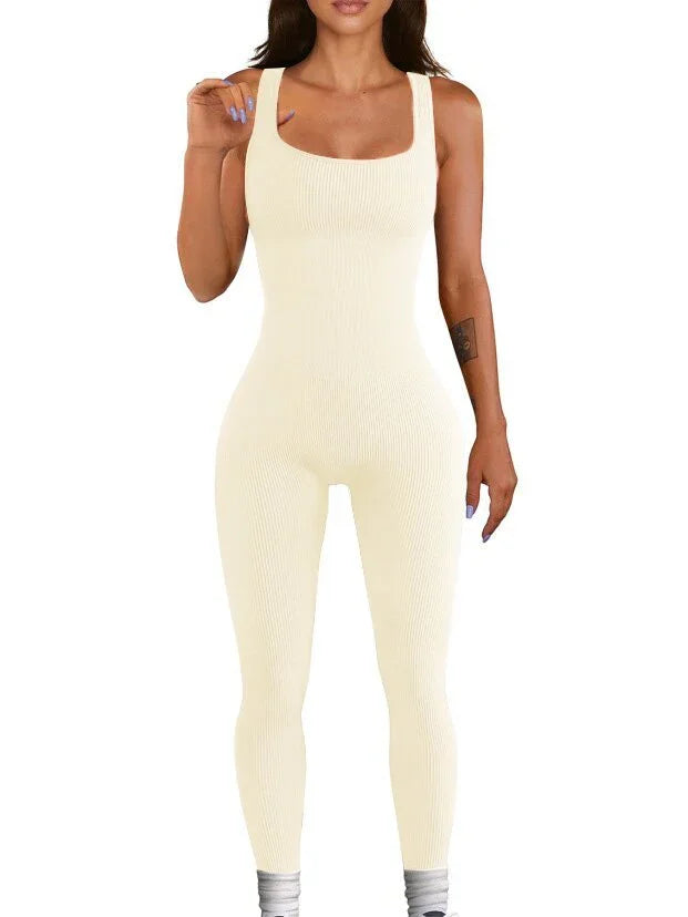 Woman wearing a cream ribbed sleeveless jumpsuit, fitted, with square neckline and leggings style.