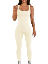 Woman wearing a cream ribbed sleeveless jumpsuit, fitted, with square neckline and leggings style.