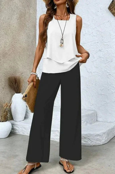 Woman wearing a sleeveless white layered top with loose black wide-leg pants, casual chic style