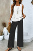 Woman wearing a sleeveless white layered top with loose black wide-leg pants, casual chic style