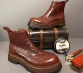 Brown leather ankle boots with chunky soles, glossy finish, and relaxed fit, displayed with shoe polish and brush.
