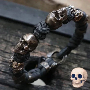 Black paracord bracelet with metallic skull beads, rugged streetwear accessory.