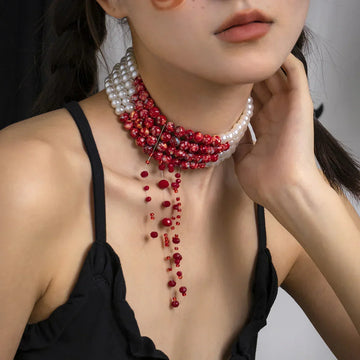 Woman wearing black spaghetti strap top with layered red and white beaded choker necklace