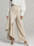 Beige wide-leg textured pants with asymmetrical ruffle overlay and high waist, paired with a white blouse.