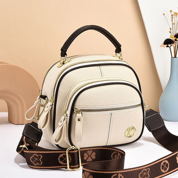 Cream faux leather crossbody bag with gold zippers, brown adjustable strap, structured fit