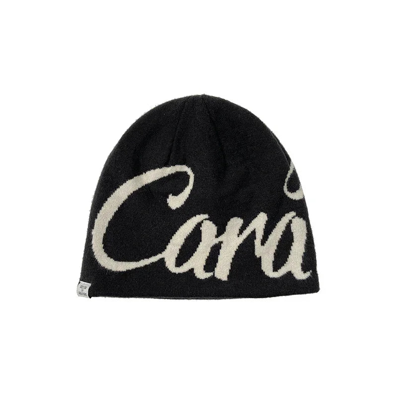 Black knit beanie with white script lettering, soft material, relaxed fit streetwear hat