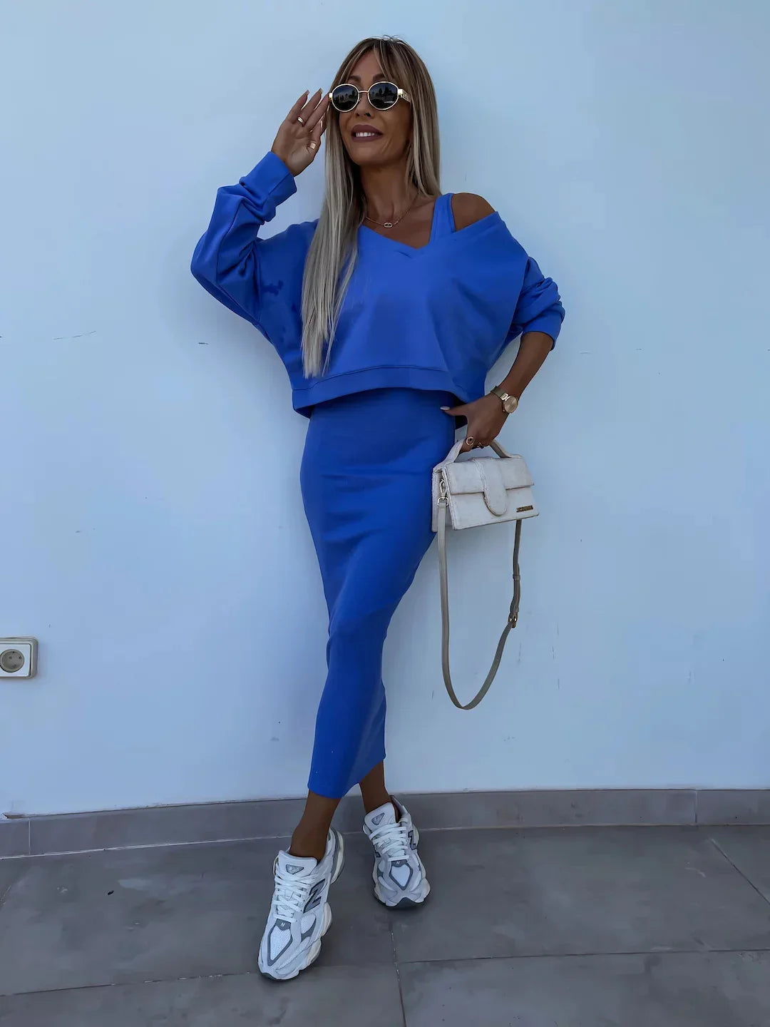 Woman in blue two-piece skirt set with off-shoulder top, midi skirt, and chunky sneakers