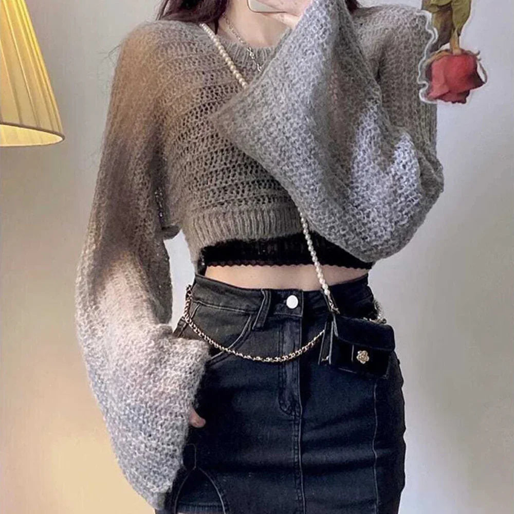 Gray knit cropped sweater with wide sleeves and black high-waisted denim skirt, modern streetwear style.