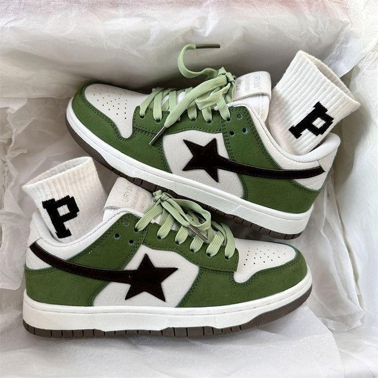 Green and white low-top sneakers with black star detail and light green laces, paired with white ribbed socks featuring a black P letter, displayed on white tissue paper.