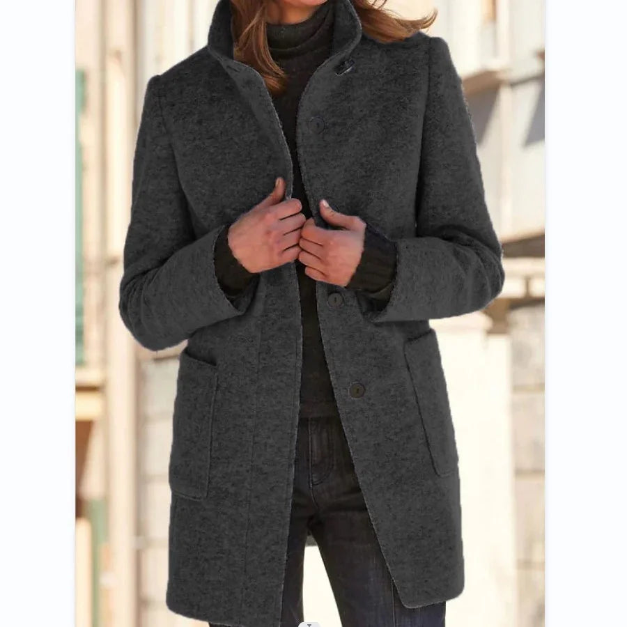 Woman wearing a dark gray wool coat with a tailored fit and flap pockets.