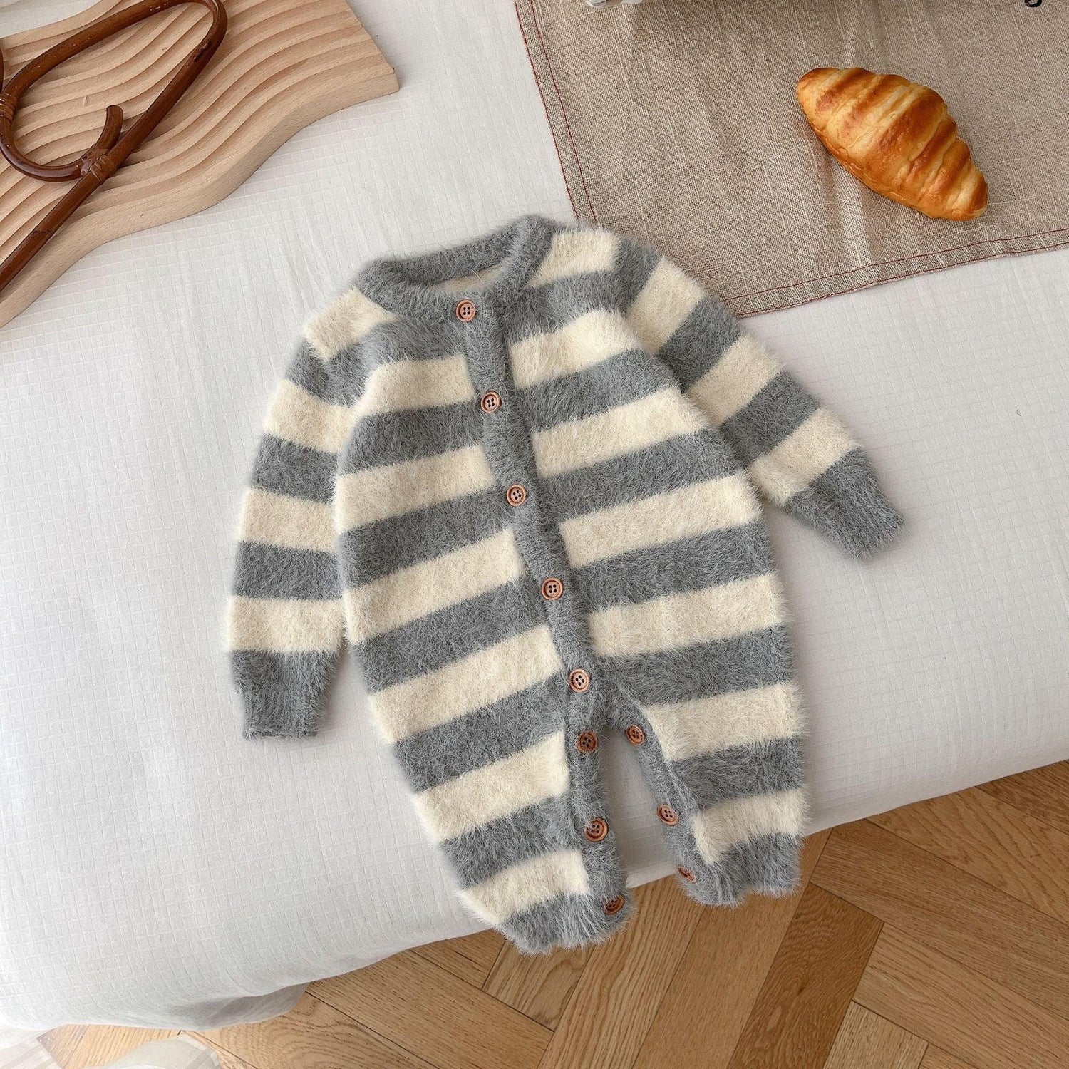 Fuzzy gray and white striped baby romper with long sleeves and wooden buttons, laid flat