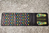 Black acupressure mat with colorful massage nodes and foot reflexology chart, laid on stone floor.