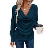 Woman wearing a teal draped cowl neck long sleeve top and fitted blue jeans