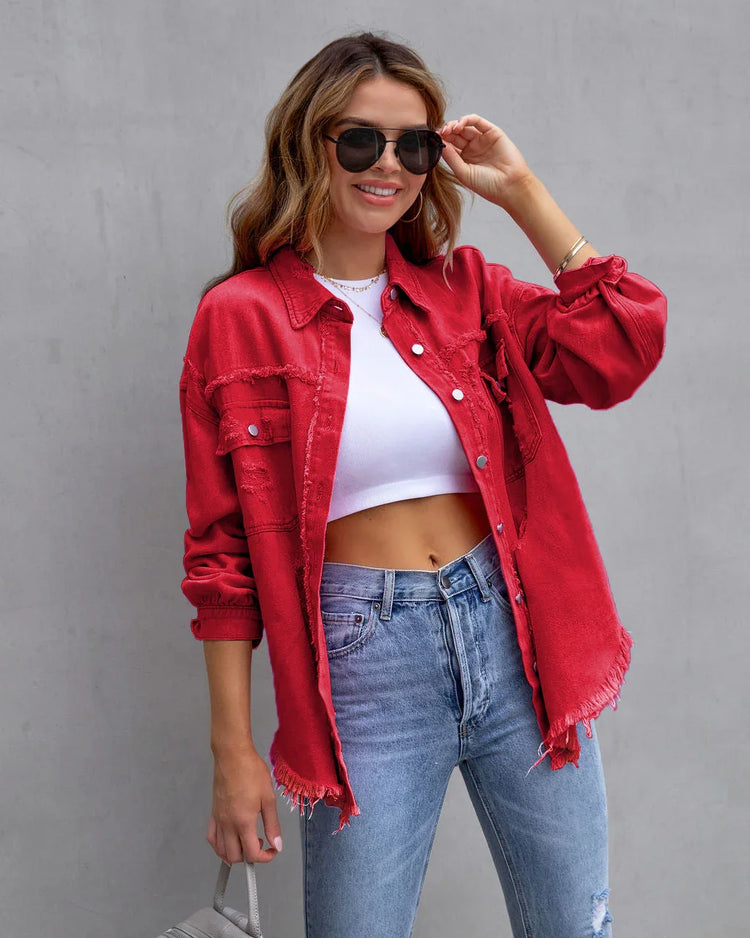 Woman in casual streetwear with red distressed oversized denim jacket, white crop top, blue jeans