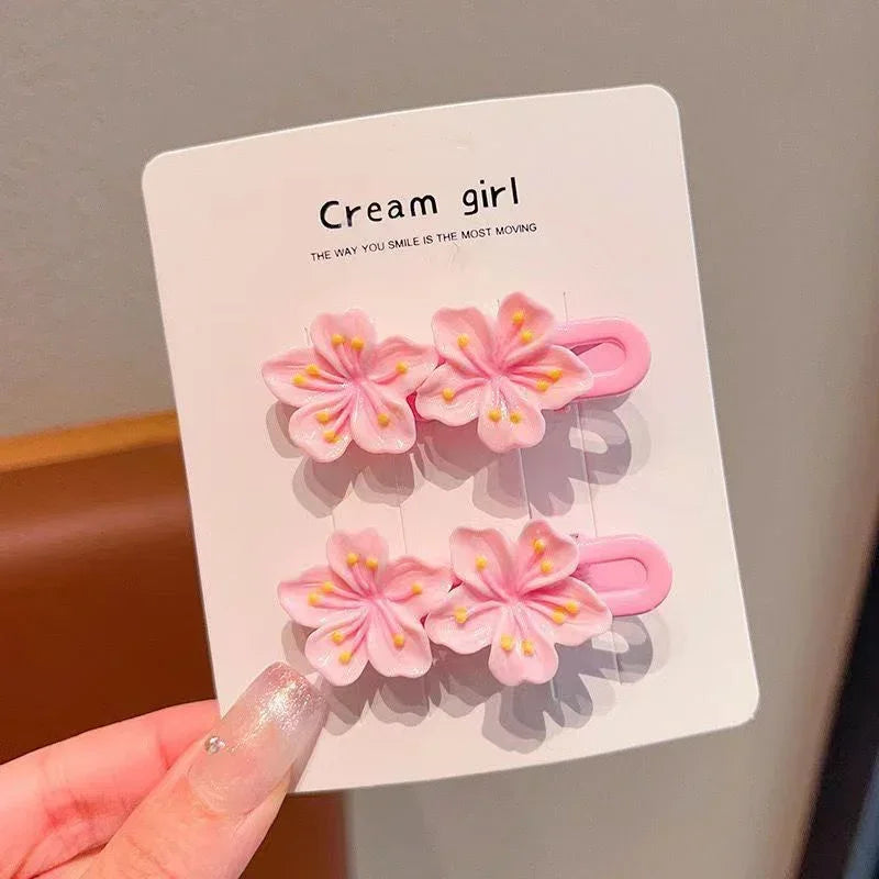 Pair of pink flower-shaped hair clips with pastel plastic design on display card
