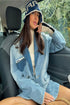 Woman in oversized light blue denim jacket and bucket hat, wearing a beige turtleneck sweater.