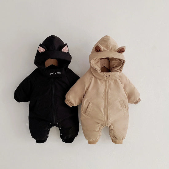 Two hooded baby jumpsuits, one black with cat ears and one beige with bear ears, padded, relaxed fit.